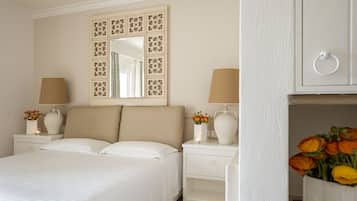Una camera da letto ordinata con un letto, due comodini, uno specchio e un tavolino con un vaso di fiori.