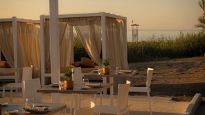 A beachside restaurant with outdoor seating, white tables, and chairs, and a view of the sea. - Ostuni a Mare (Ostuni)
