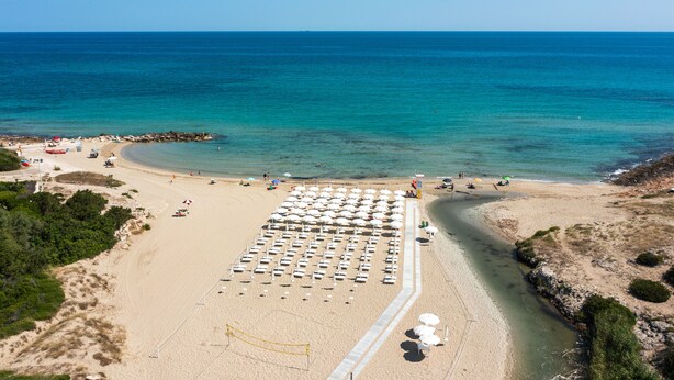 A beach with rows of sunbeds and umbrellas, a sandy shore, and the ocean in the background. - Ostuni a Mare (Ostuni)