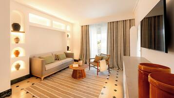 Una sala de estar moderna con sofá, sillón, mesa de centro y televisor de pantalla plana.