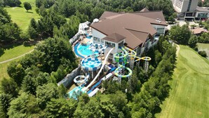 Ein großes Resort mit Wasserpark, einschließlich Rutschen und Pools, umgeben von üppiger Vegetation.