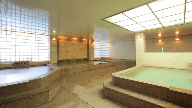 Ein traditionelles japanisches Onsen mit mehreren Thermalbädern, Steinstufen und Kachelwänden.