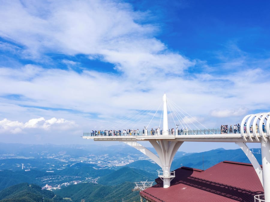 Un pont à haubans sur lequel des personnes se promènent, offrant une vue sur un paysage montagneux.