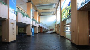 Un vaste atrium doté d’un escalier central, de lambris en bois et d’une grande bannière publicitaire pour une station de sports d’hiver.