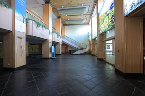Un vaste atrium doté d’un escalier central, de lambris en bois et d’une grande bannière publicitaire pour une station de sports d’hiver.
