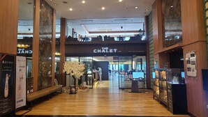 Un intérieur moderne avec un plancher en bois, un espace salon central et un restaurant bien visible appelé « Le Chalet ».