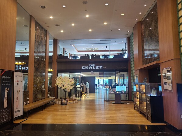 Un intérieur moderne avec un plancher en bois, un espace salon central et un restaurant bien visible appelé « Le Chalet ».