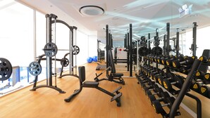 Ein Fitnessraum mit verschiedenen Kraftgeräten, Spiegelwänden und Holzboden.