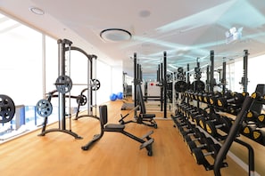 Een sportschool met diverse gewichthefapparaten, spiegelwanden en een houten vloer.