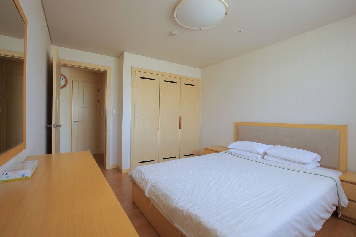 Un dormitorio con cama, armario de madera y mesita de noche.