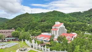 A hotel with multiple buildings, surrounded by lush greenery and a mountainous backdrop.