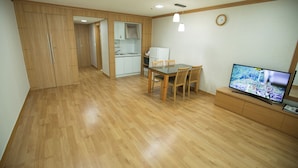 Una cocina moderna con armarios de madera, un comedor con mesa y sillas, y un televisor sobre un mueble de madera.