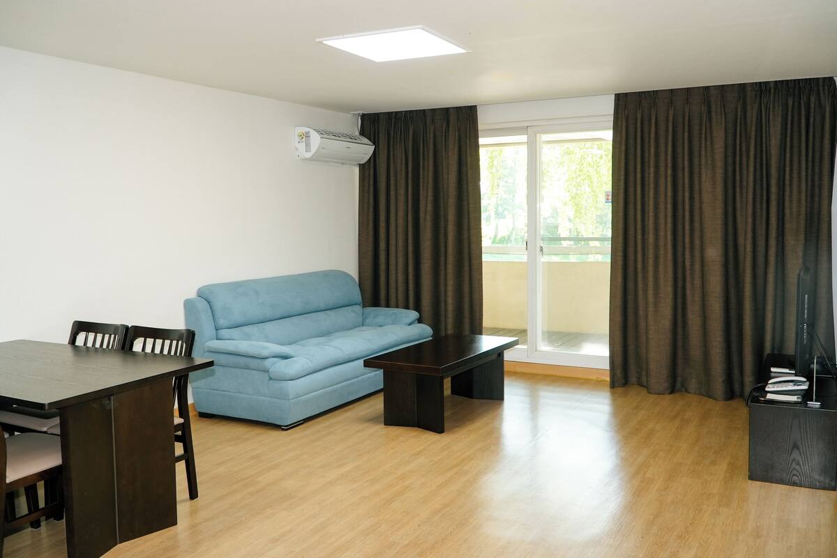 Una sala moderna con una mesa de comedor, un sofá azul y una mesa de centro de madera oscura.