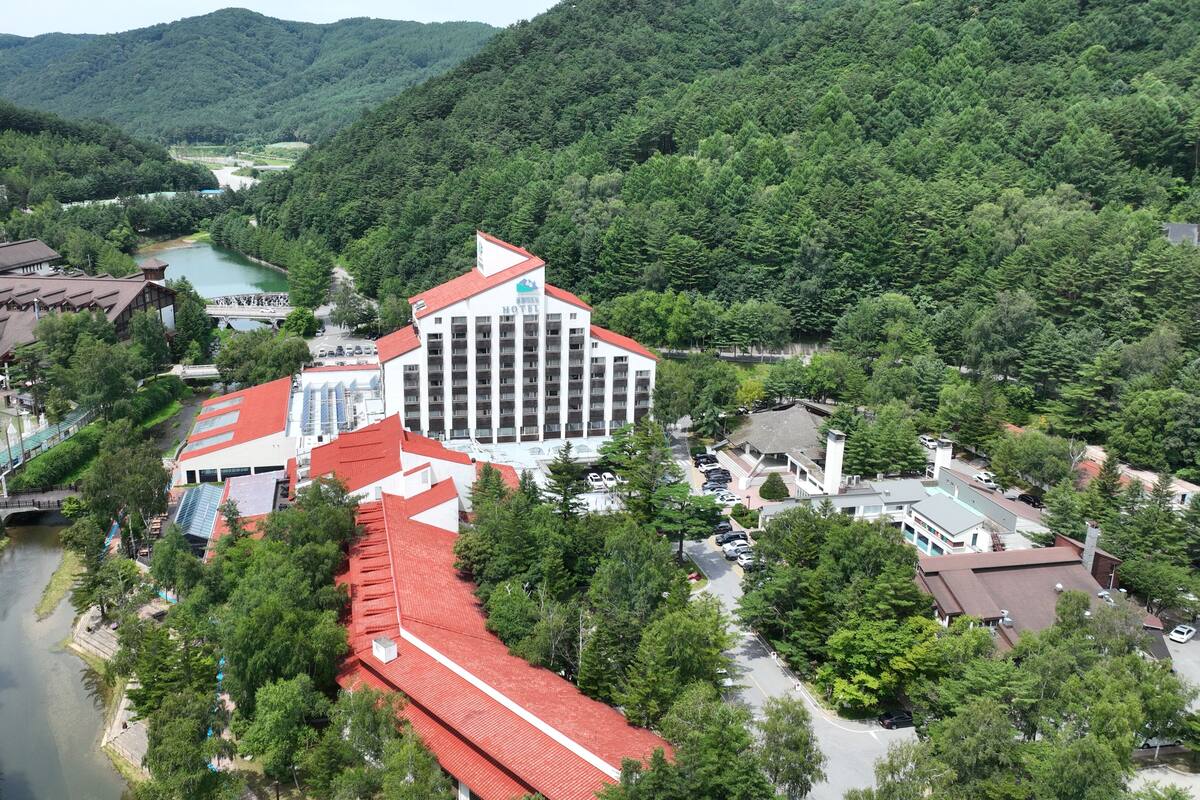 Un hotel con varias edificaciones, un río y follaje circundante.