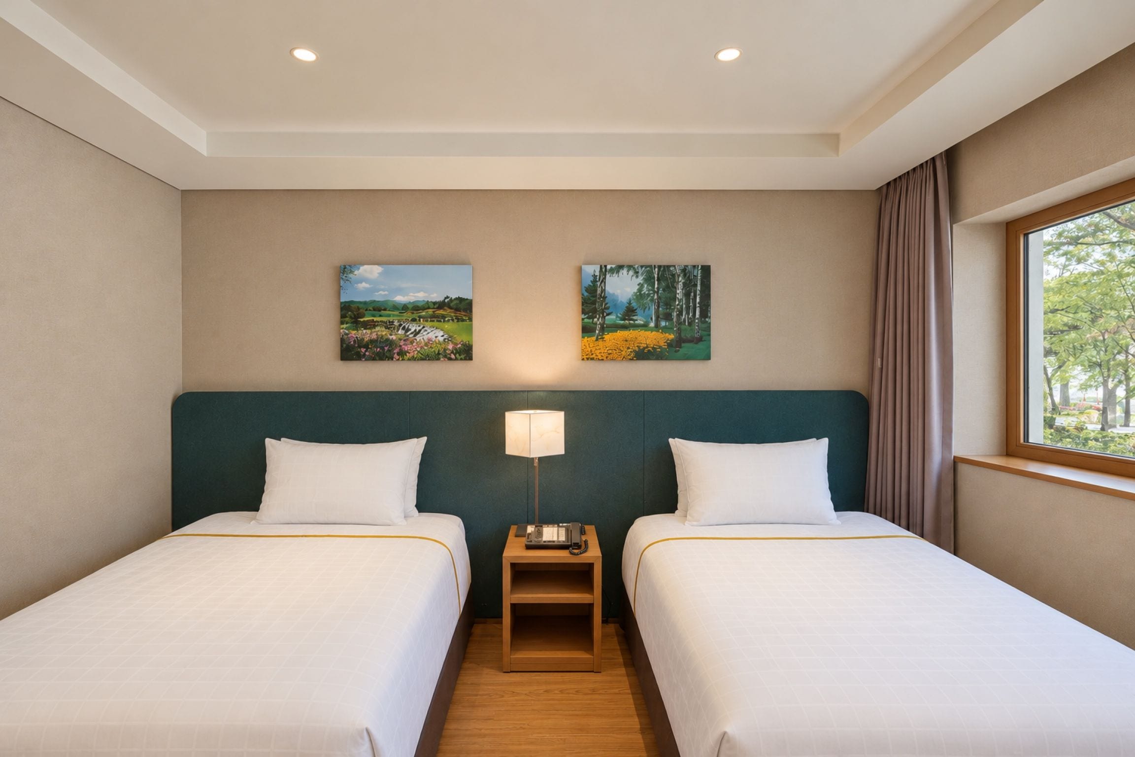 A hotel room with two beds, a nightstand, a lamp, and two paintings on the wall.