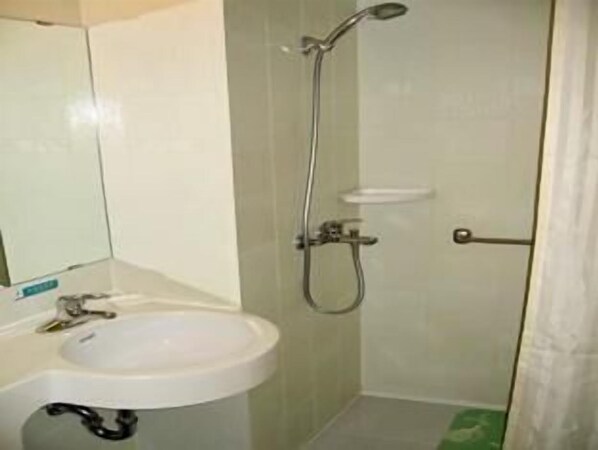 A small bathroom with a sink, mirror, and shower.