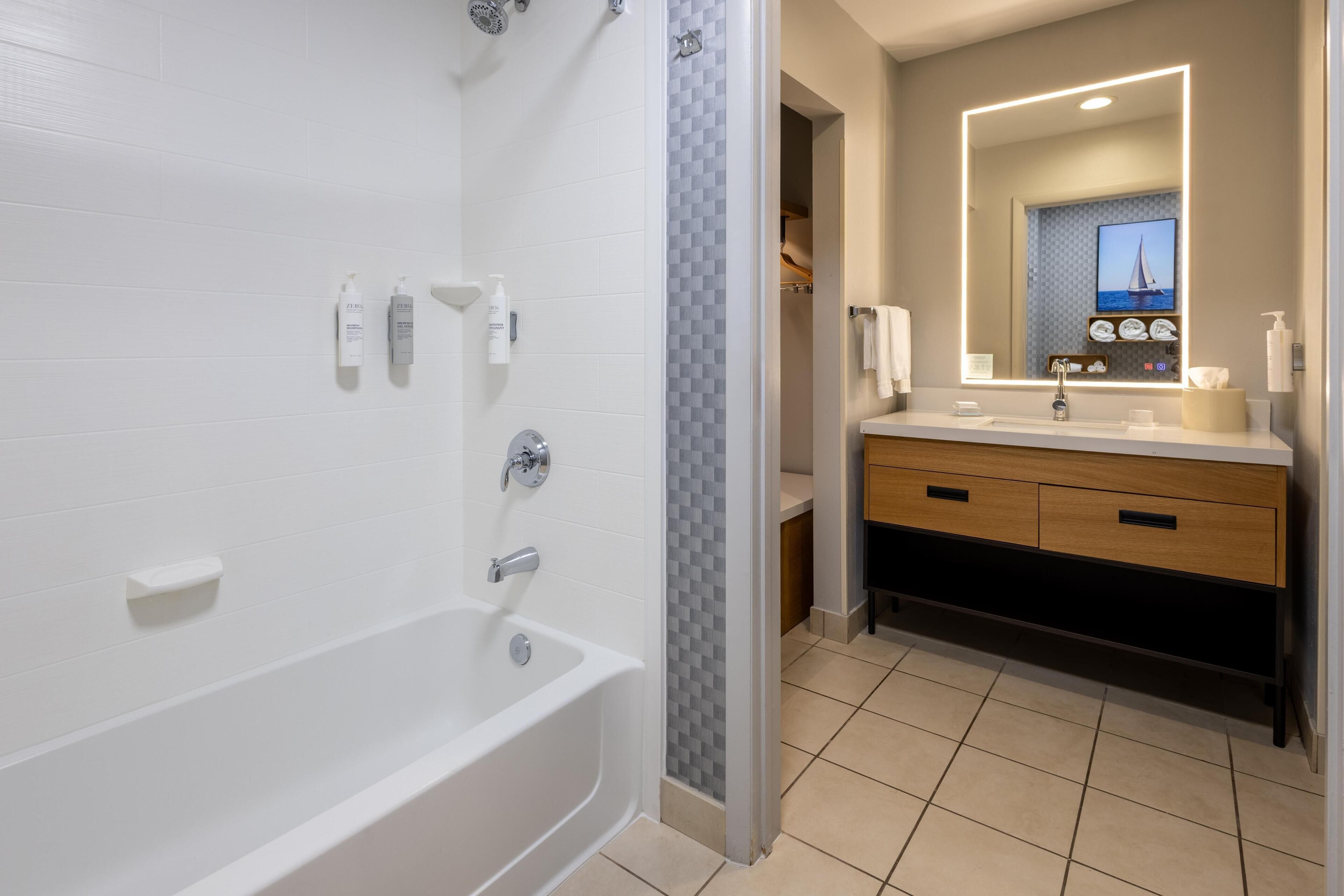 A modern bathroom with a bathtub, a shower, and a vanity with a mirror.