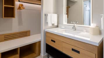 Un bagno moderno con un lavandino bianco, un mobile vanitario in legno e uno specchio sopra il lavandino.
