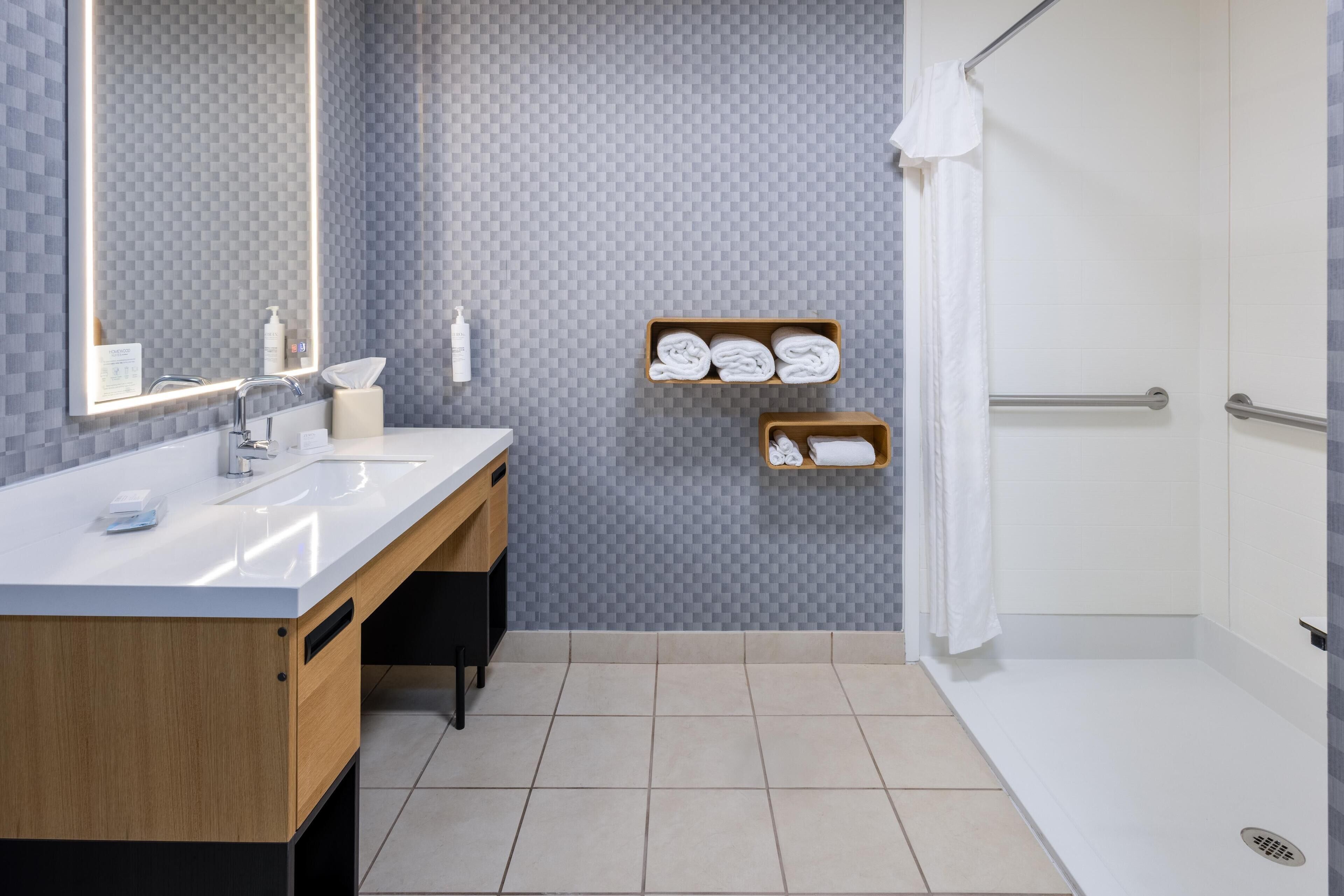 Une salle de bain moderne avec un lavabo blanc, un meuble-lavabo en bois et un espace douche.