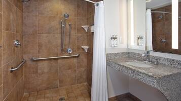 A bathroom with a shower, grab bars, a sink, and a mirror.
