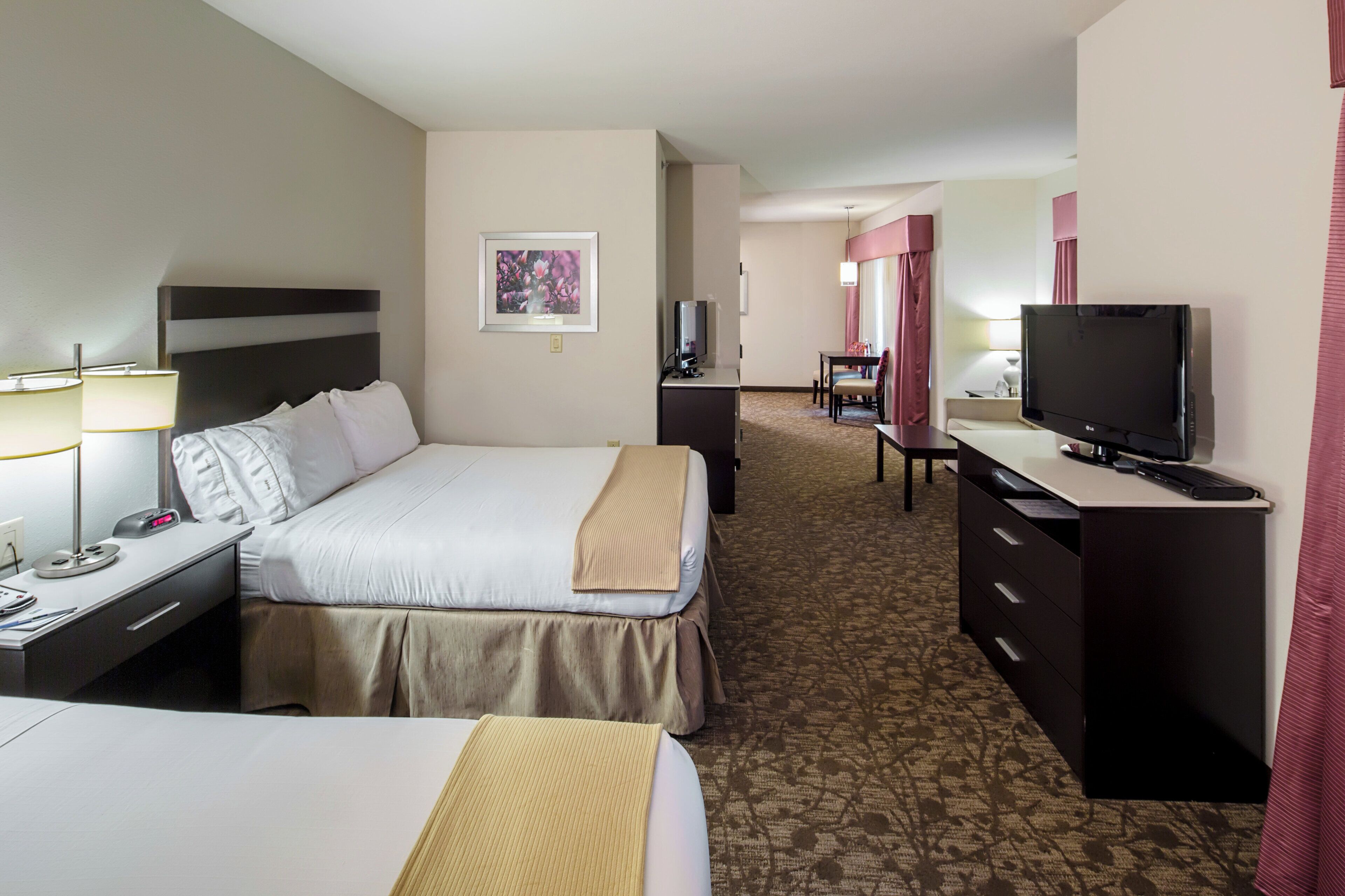 A hotel room with a bed, bedside table, lamp, TV, desk, and a mirror.