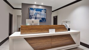 A reception desk with a modern design, featuring a white and wooden finish. A Holiday Inn Express sign is visible above the desk, and two HP computers are placed on the desk. - Holiday Inn Express Augusta North by IHG (Augusta)