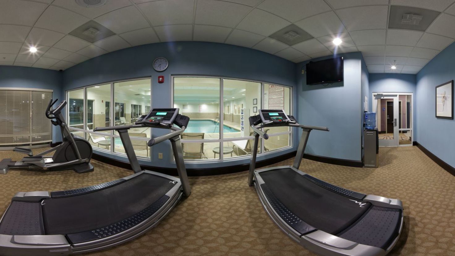 A fitness room with treadmills, a pool, and a TV.
