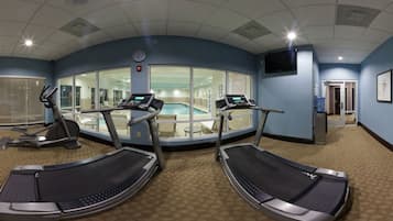 A fitness room with treadmills, a pool, and a TV.