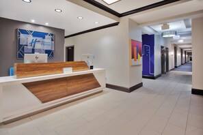 A modern hotel reception area with a wooden reception desk, a digital display, and a sign for Holiday Inn Express. - Holiday Inn Express Augusta North by IHG (Augusta)