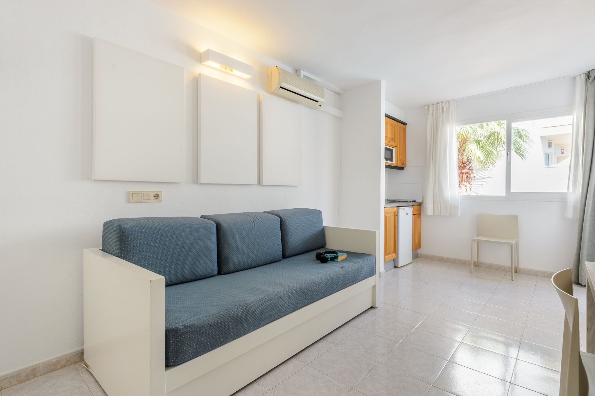 Una sala de estar moderna con un sofá, una mesita y una zona de cocina al fondo.
