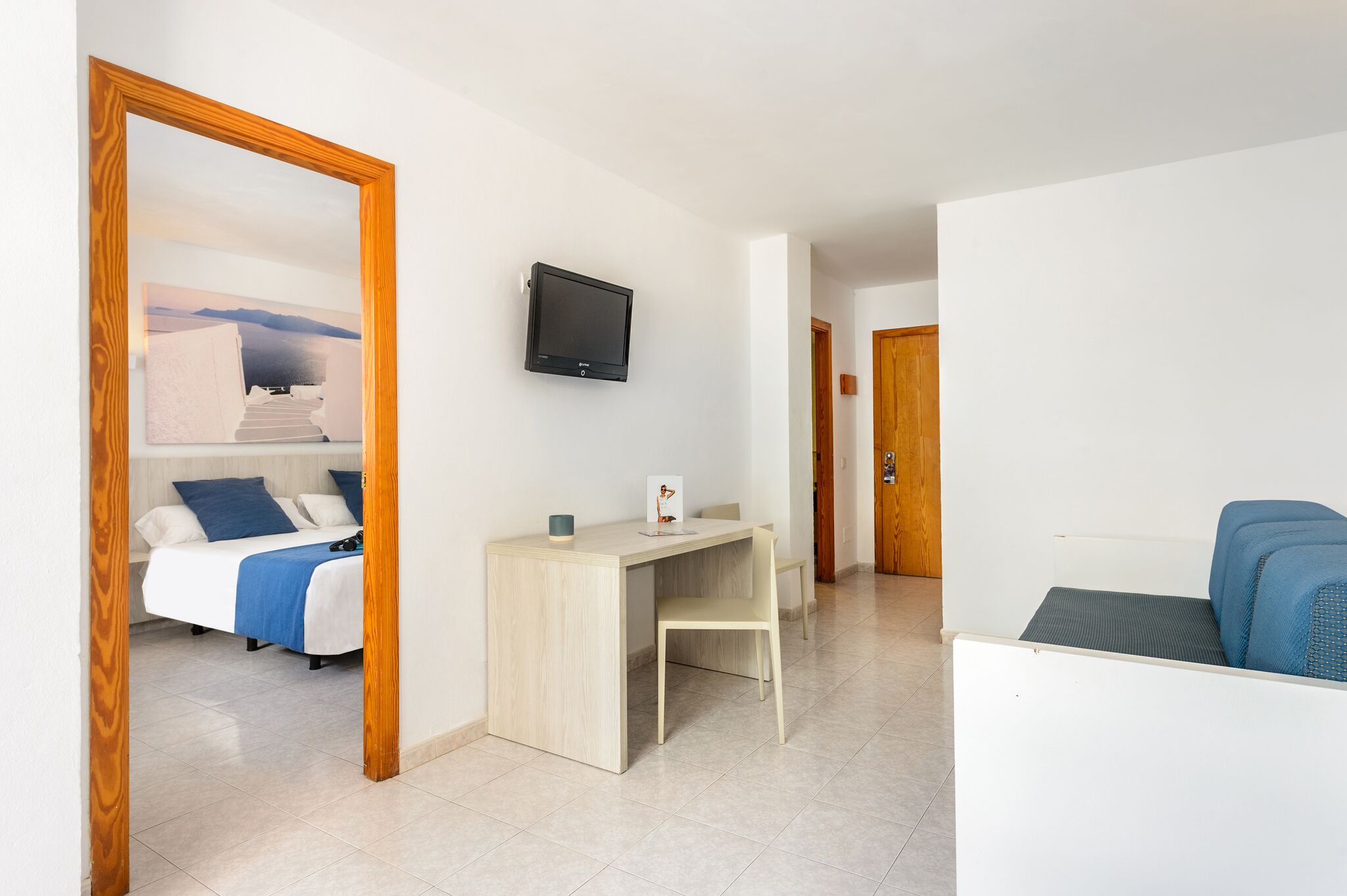 Una habitación con cama, escritorio, silla, televisor y sofá.
