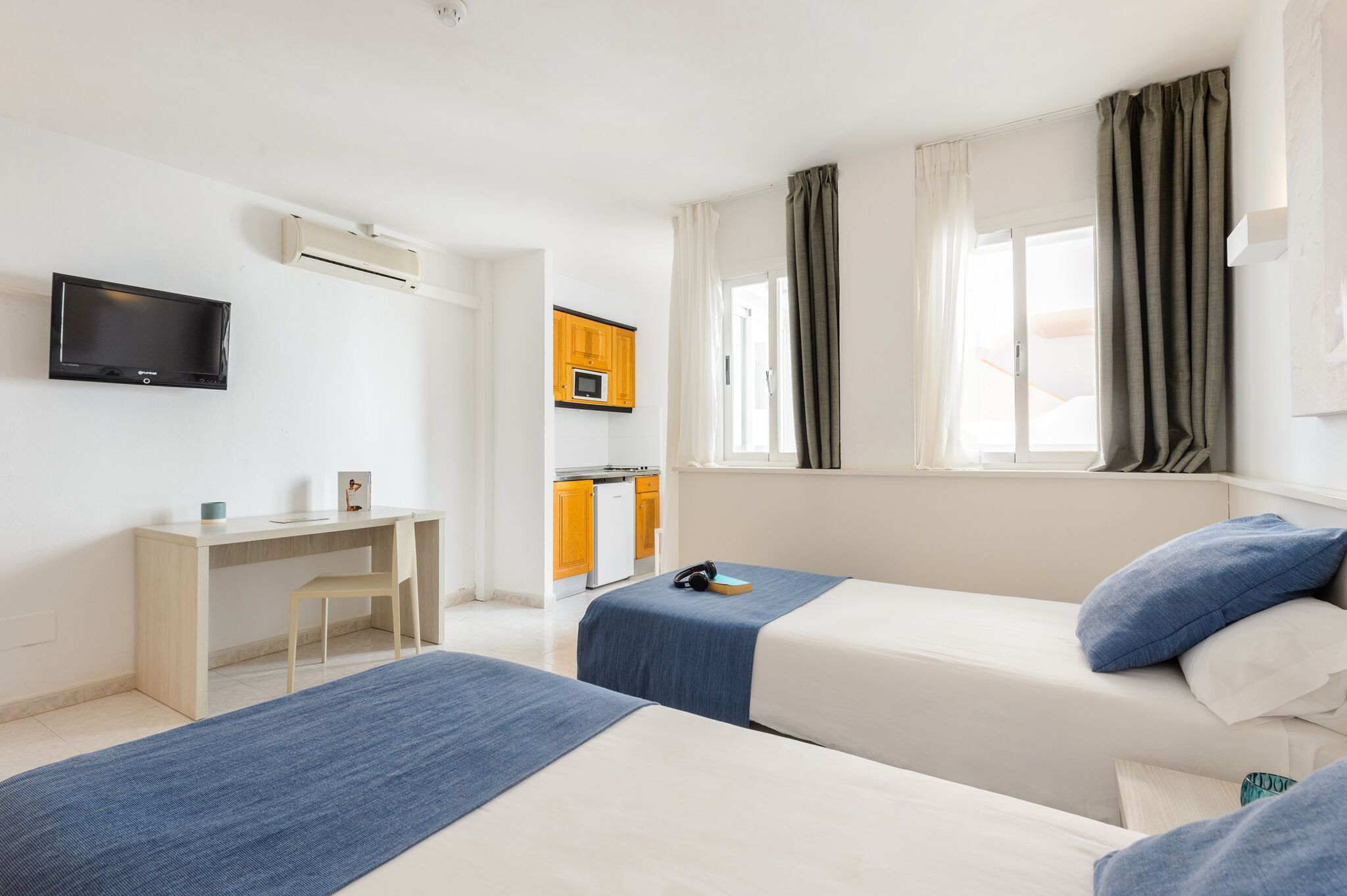 Une chambre d’hôtel avec deux lits, un bureau, une télévision et une kitchenette.