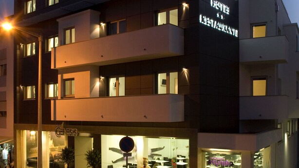 Un hotel de varios pisos con un diseño moderno, con señalización iluminada y grandes ventanales.