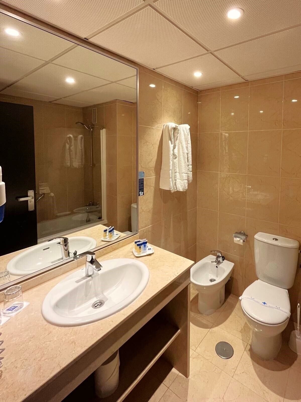 A modern bathroom with two sinks, a toilet, and a shower.