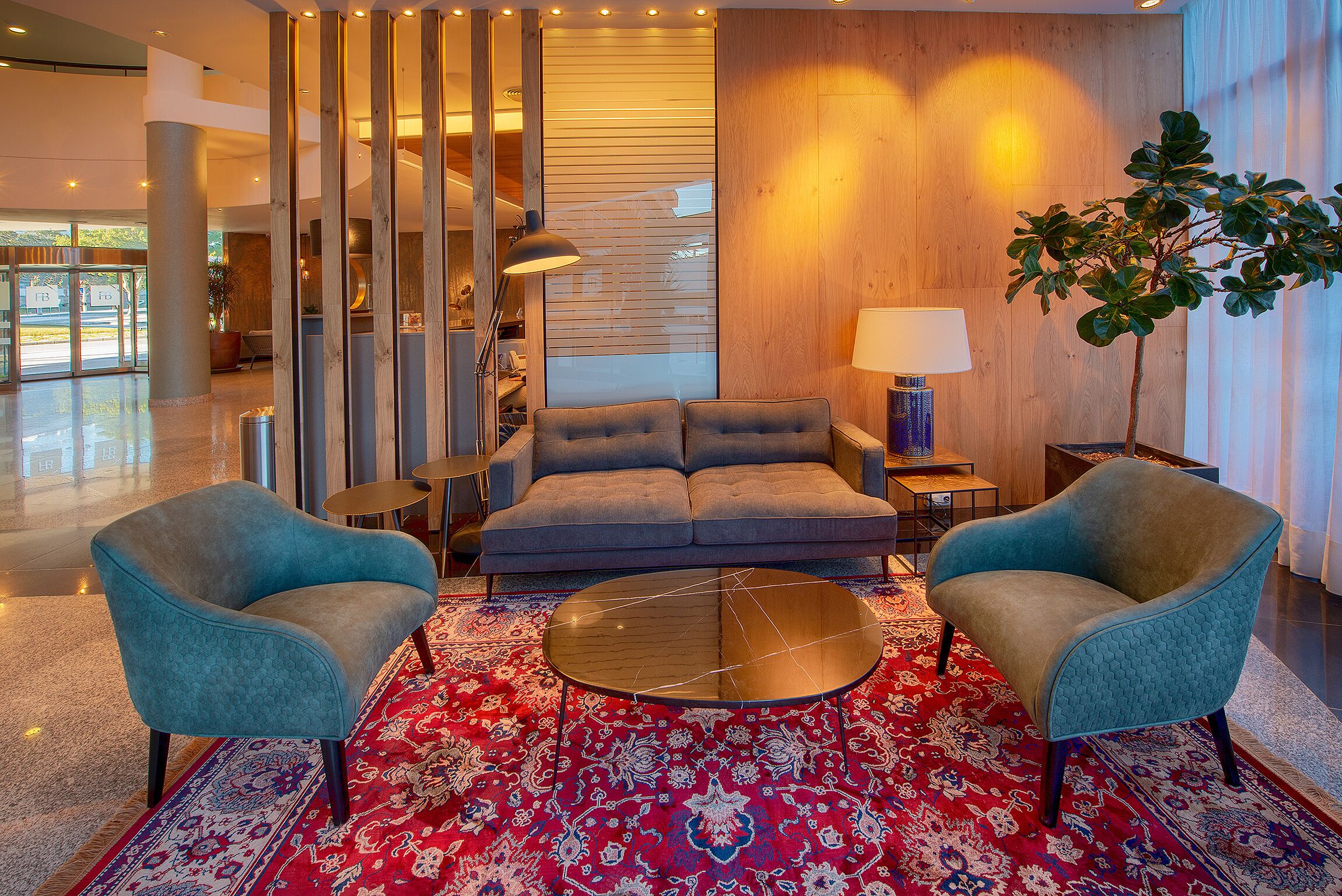 A modern lobby with a sofa, two armchairs, a coffee table, and a patterned rug.