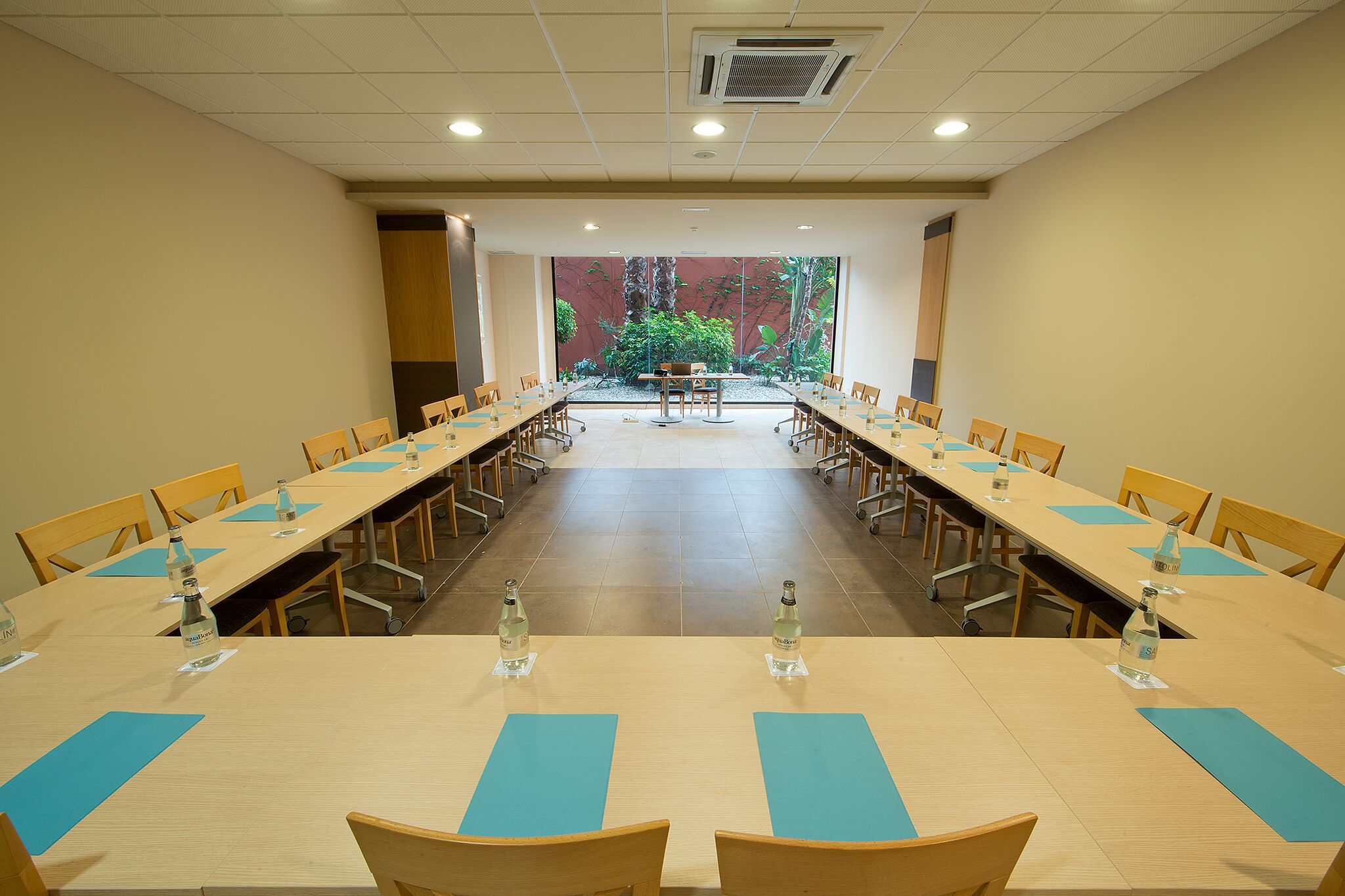 Une salle de conférence avec de longues tables, des chaises et des bouteilles d’eau.
