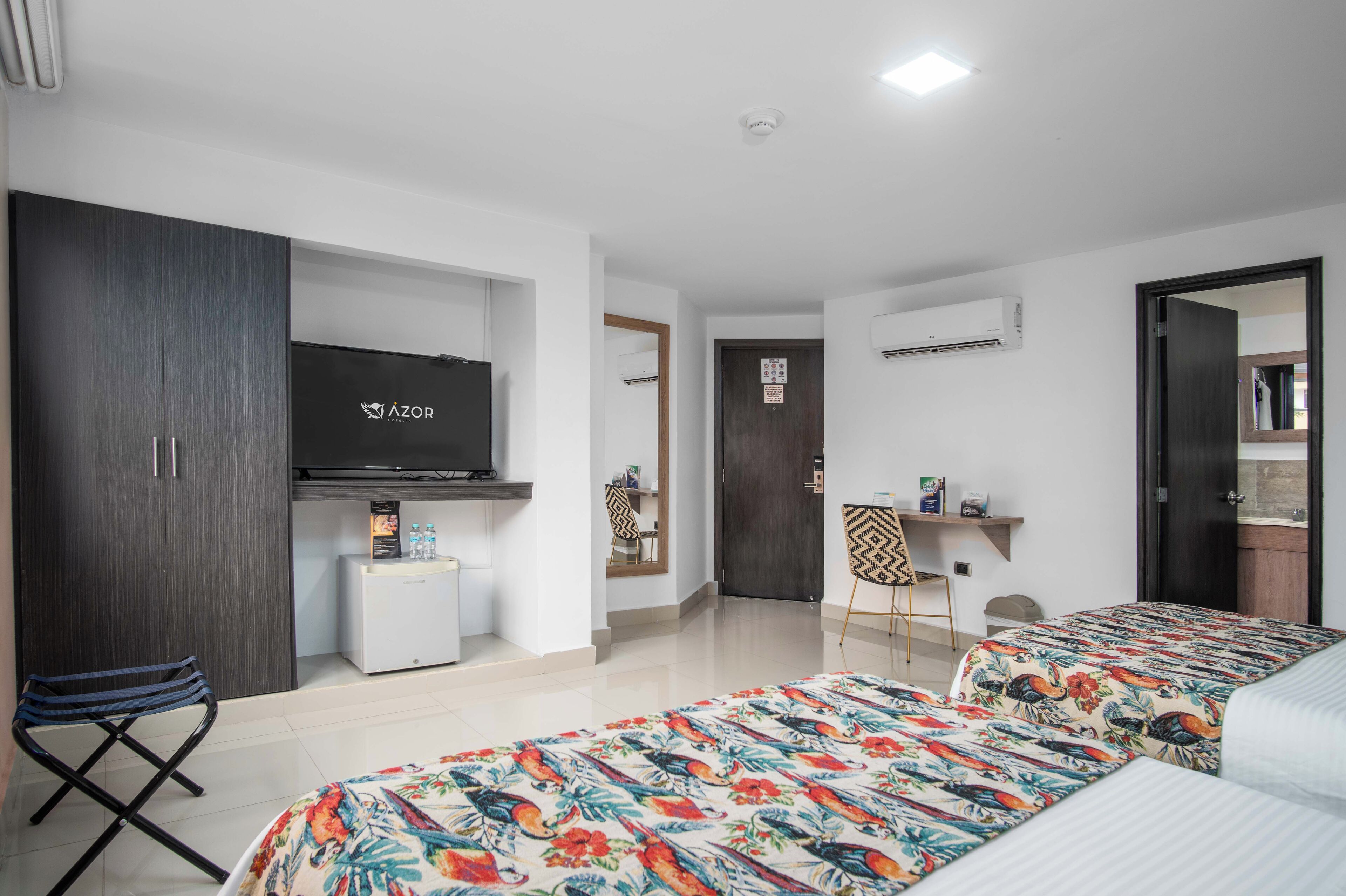A hotel room with a bed, a desk, a TV, and a wardrobe.