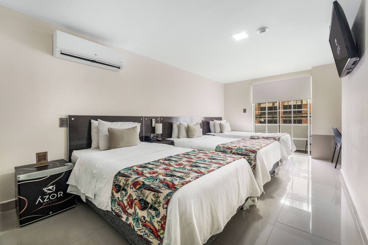 Quarto de hotel com duas camas, um minibar, ar condicionado, televisão de tela plana e uma janela com vista.