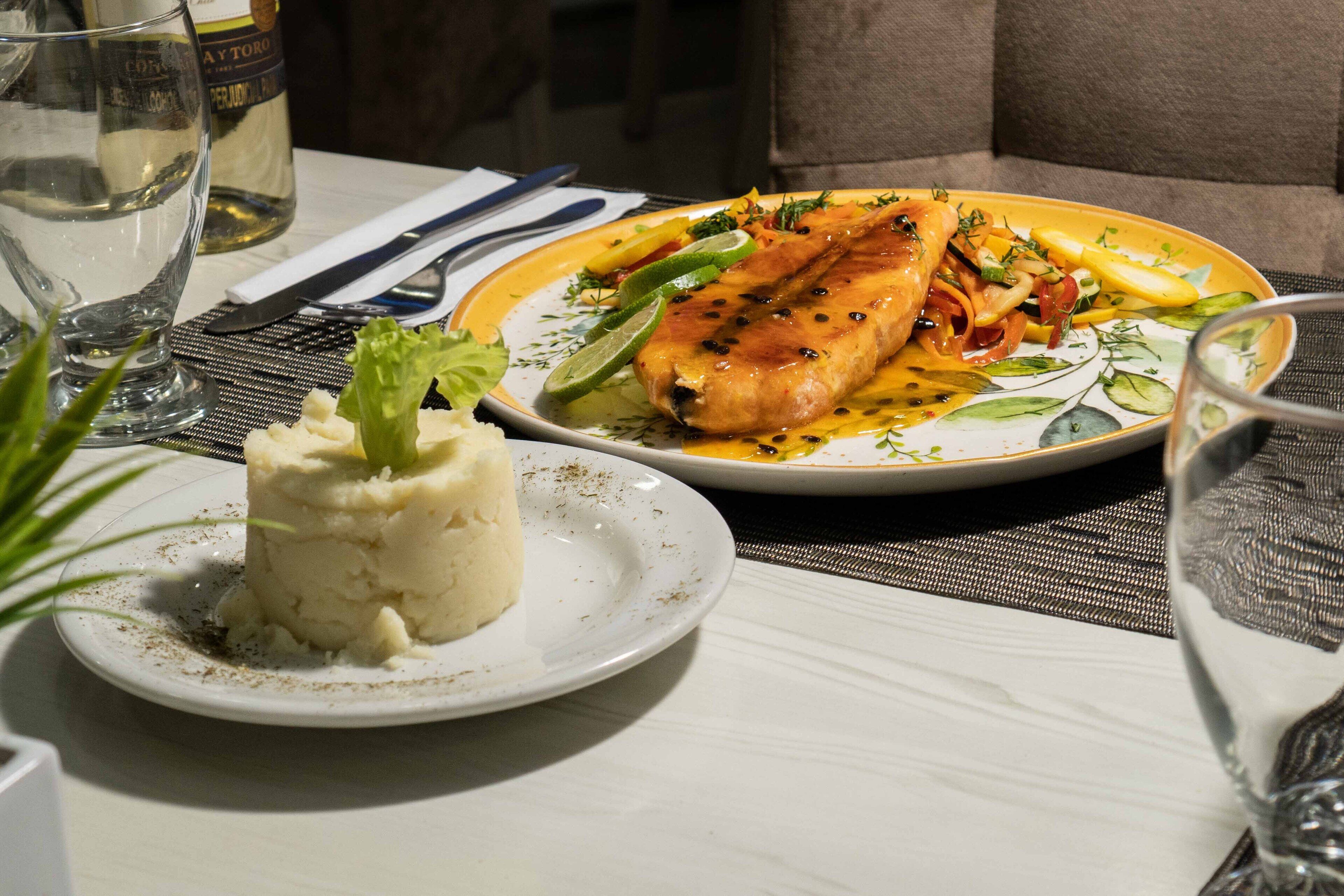 A dining table with a plate of food, a glass of water, and a bottle of wine.