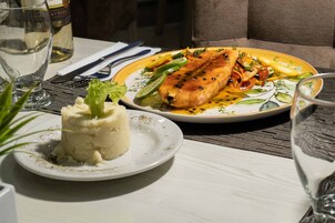 Una mesa de comedor con un plato de comida, un vaso de agua y una botella de vino.