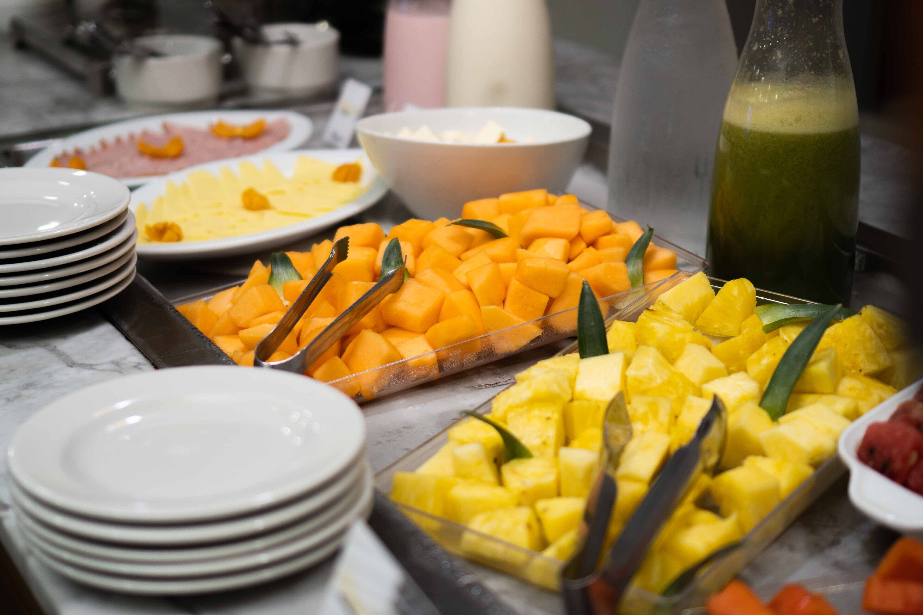 A buffet with various fruits and a green beverage.