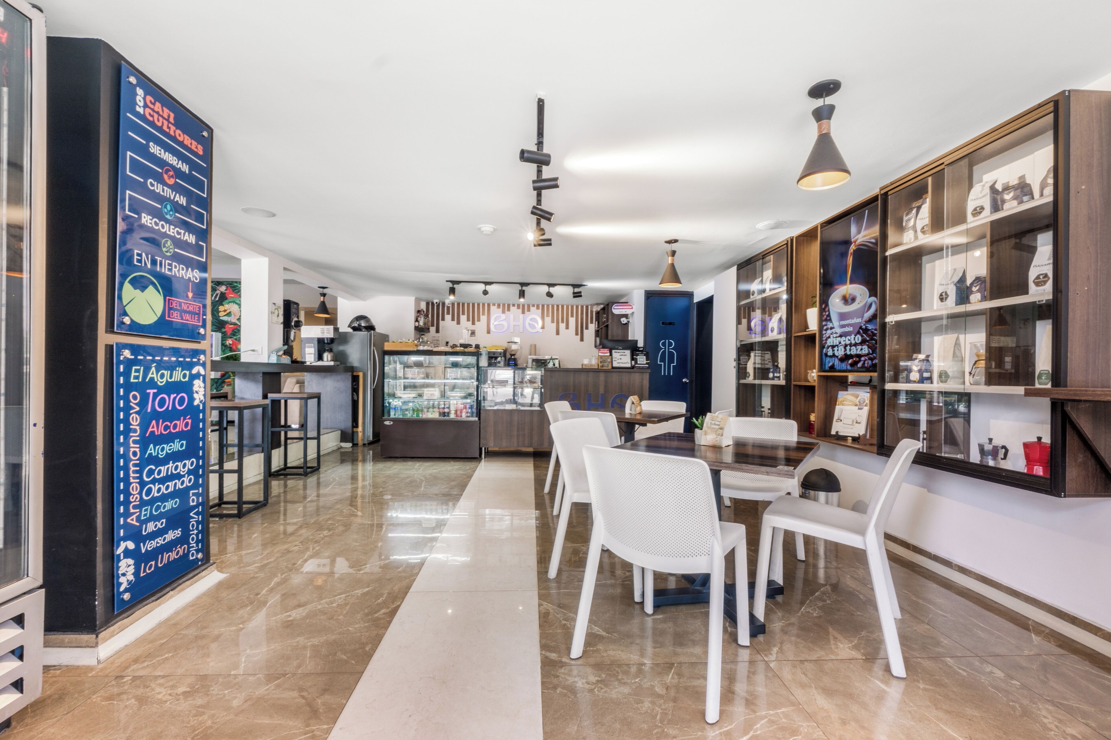 A modern cafe with a counter, seating area, and display shelves.