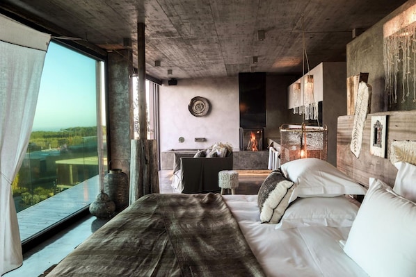 Un dormitorio moderno con una cama grande, una chimenea y vistas al exterior.