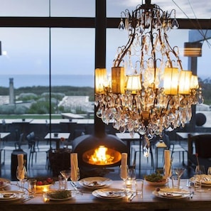 Comedor con candelabro, mesa lista para una comida y vistas al exterior.
