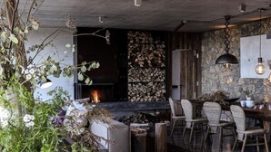 A modern interior with a fireplace, stone wall, and a dining area with chairs.