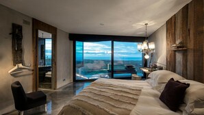 A modern bedroom with a large bed, a view of a landscape, and a small table with a chair. - Areias do Seixo Charm Hotel & Residences (Torres Vedras)