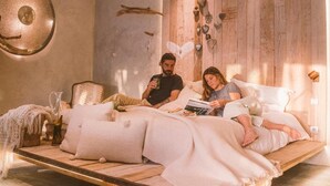 A bedroom with a wooden bed frame, a large wall clock, and decorative heart-shaped lights. - Areias do Seixo Charm Hotel & Residences (Torres Vedras)