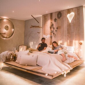 A bedroom with a wooden bed frame, a large wall clock, and decorative heart-shaped lights. - Areias do Seixo Charm Hotel & Residences (Torres Vedras)