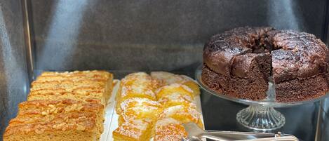 A display case with a variety of baked goods, including a chocolate cake and several types of bread.