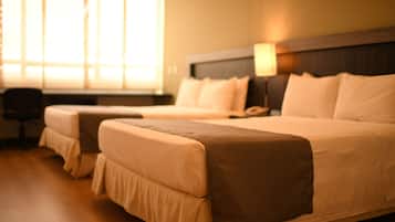 A hotel room with two beds, a desk, and a lamp.